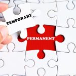 "PERMANENT" word on missing puzzle with a hand hold a piece of "TEMPORARY" word puzzle want to complete it - business and finance concept